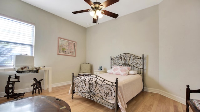 bedroom with multiple windows, ceiling fan, and hardwood / wood-style flooring