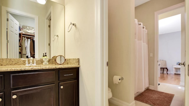 bathroom with tile patterned flooring, vanity, toilet, and walk in shower