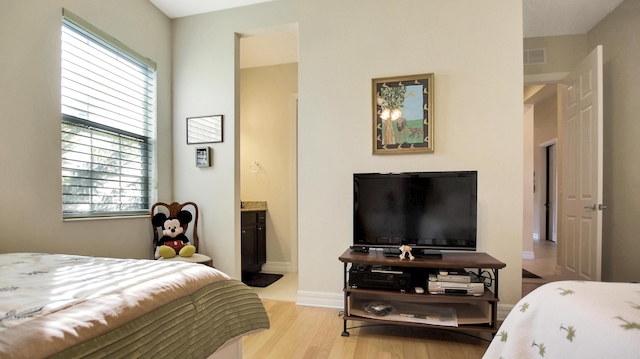 bedroom featuring light wood-type flooring and ensuite bath