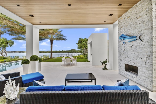 view of patio featuring an outdoor living space with a fireplace and a water view