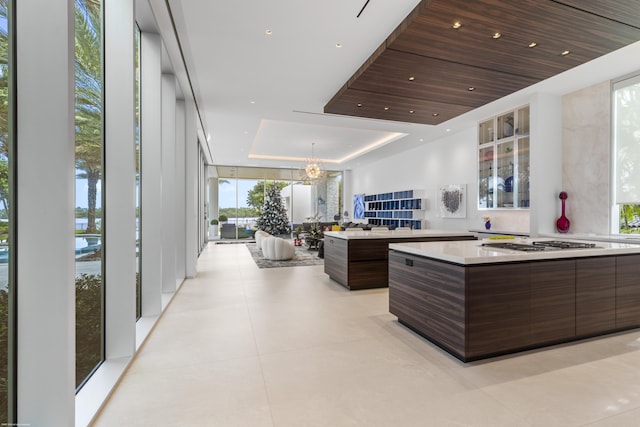 interior space with expansive windows, a tray ceiling, dark brown cabinets, a kitchen island, and wood ceiling