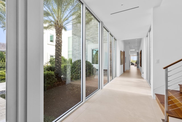 hallway with light tile patterned floors and floor to ceiling windows