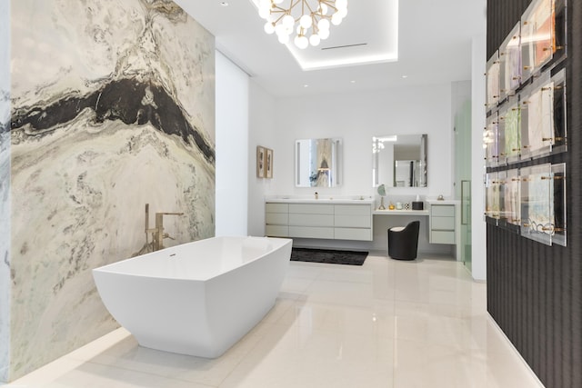 bathroom with vanity, a raised ceiling, a tub, and a chandelier