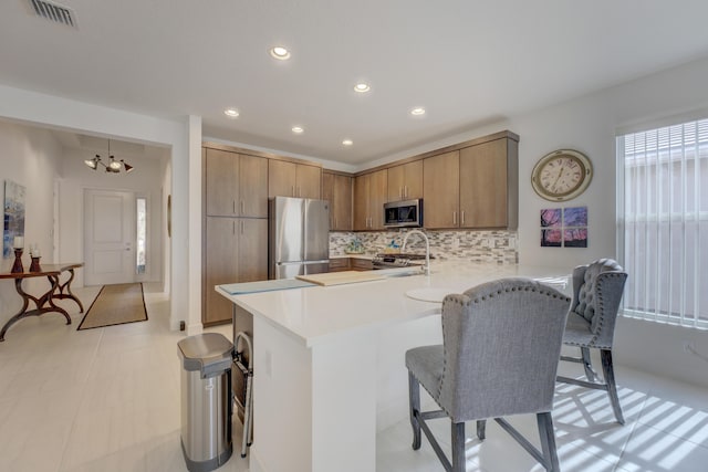 kitchen featuring a breakfast bar, tasteful backsplash, a chandelier, kitchen peninsula, and stainless steel appliances