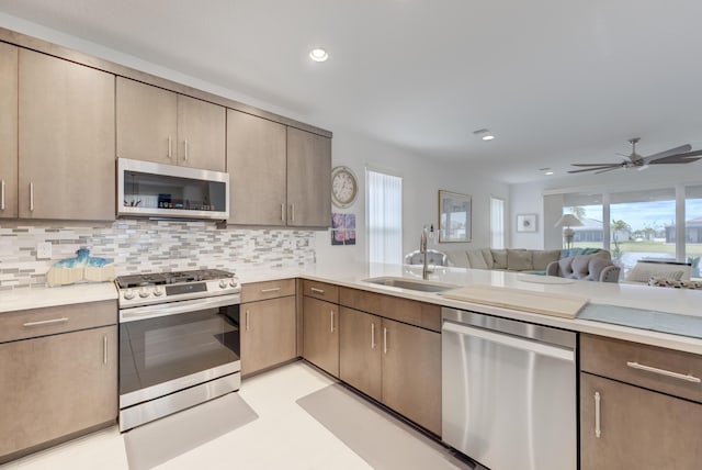 kitchen featuring appliances with stainless steel finishes, sink, ceiling fan, and decorative backsplash