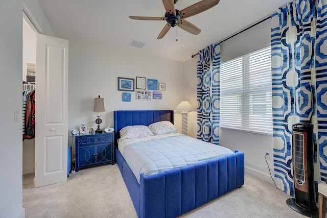 bedroom with light carpet, a spacious closet, and ceiling fan