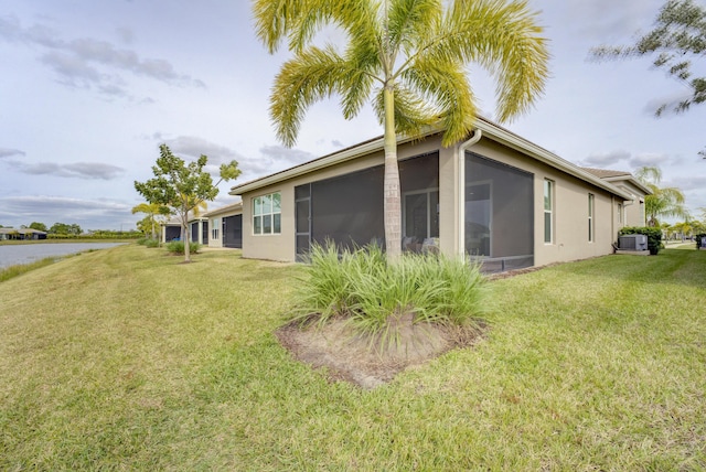 back of property featuring a yard, central AC, a sunroom, and a water view