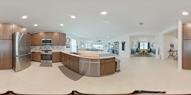 kitchen featuring sink, tasteful backsplash, appliances with stainless steel finishes, kitchen peninsula, and ceiling fan