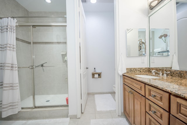 bathroom featuring tile patterned floors, vanity, toilet, and a shower with door