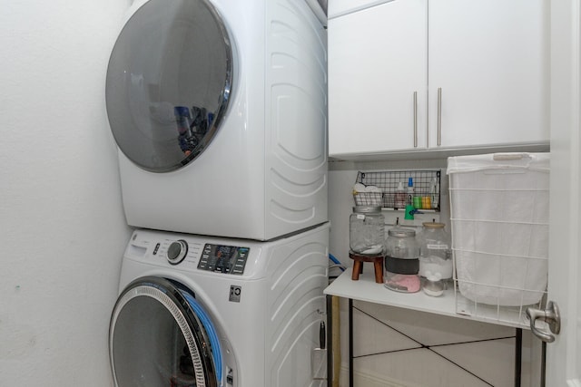 washroom with cabinets and stacked washing maching and dryer