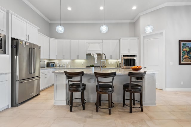 kitchen with white cabinets, stainless steel appliances, and an island with sink