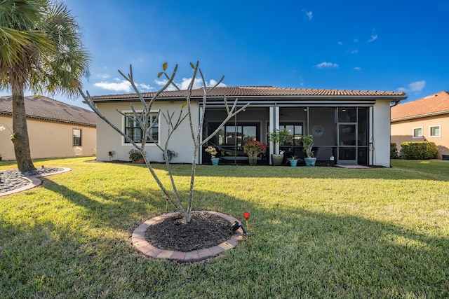 rear view of house featuring a sunroom and a lawn