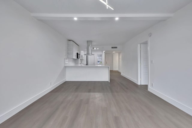 unfurnished living room with visible vents, baseboards, wood finished floors, beamed ceiling, and a sink