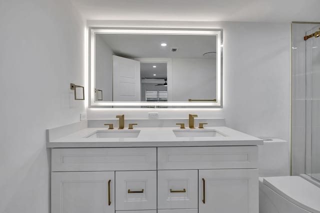 full bathroom featuring double vanity, walk in shower, a sink, and toilet