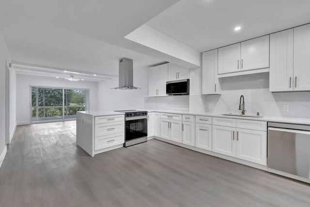 kitchen featuring decorative light fixtures, sink, white cabinets, island exhaust hood, and stainless steel appliances