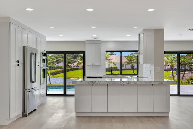 kitchen featuring a wealth of natural light, stainless steel appliances, light stone counters, and tasteful backsplash