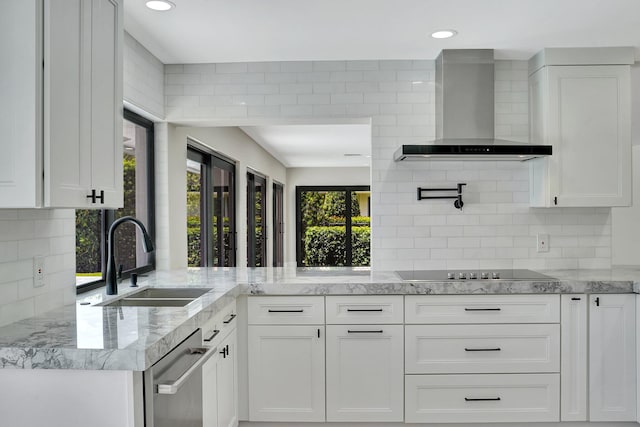 kitchen with white cabinetry, sink, and wall chimney range hood