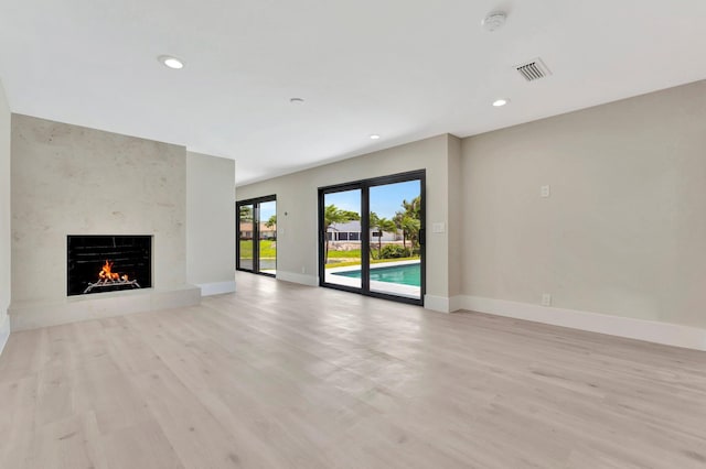 unfurnished living room with a large fireplace and light hardwood / wood-style flooring