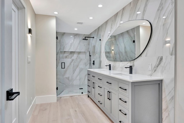 bathroom with hardwood / wood-style flooring, tile walls, a shower with shower door, and vanity