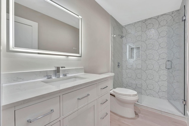 bathroom with toilet, a shower with shower door, hardwood / wood-style flooring, and vanity