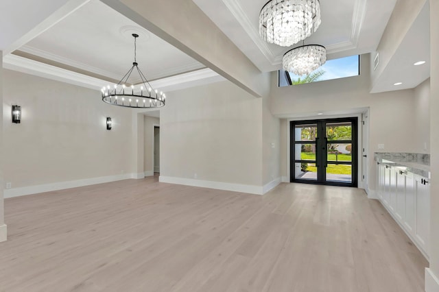 foyer with a tray ceiling, light wood-type flooring, french doors, and an inviting chandelier