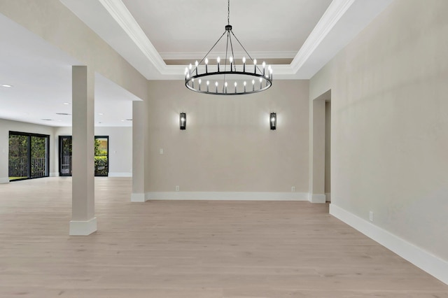 unfurnished dining area featuring crown molding, light hardwood / wood-style flooring, a raised ceiling, and a notable chandelier