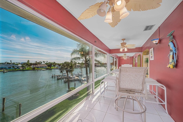 unfurnished sunroom with ceiling fan and a water view