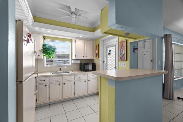 kitchen with light tile patterned floors, white fridge, crown molding, and sink