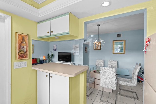 kitchen featuring kitchen peninsula, ornamental molding, light tile patterned floors, decorative light fixtures, and white cabinetry