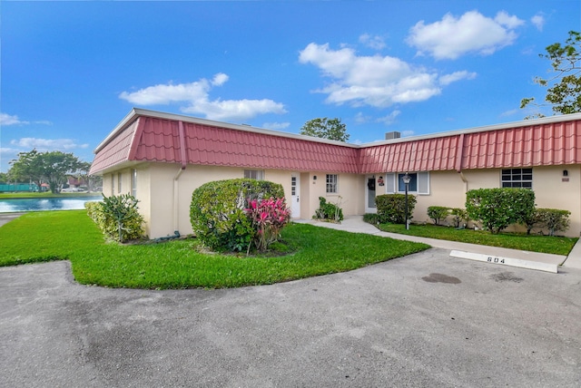 single story home with a water view and a front lawn