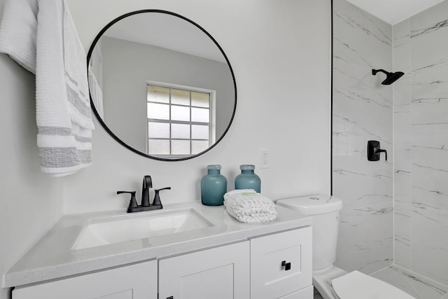 bathroom featuring a tile shower, vanity, and toilet