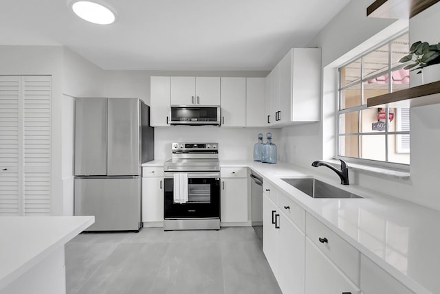 kitchen featuring stainless steel appliances, white cabinetry, and sink