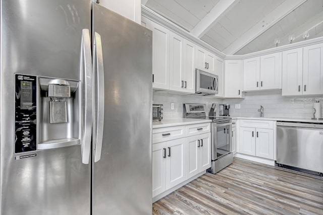 kitchen featuring white cabinets, lofted ceiling with beams, stainless steel appliances, and sink