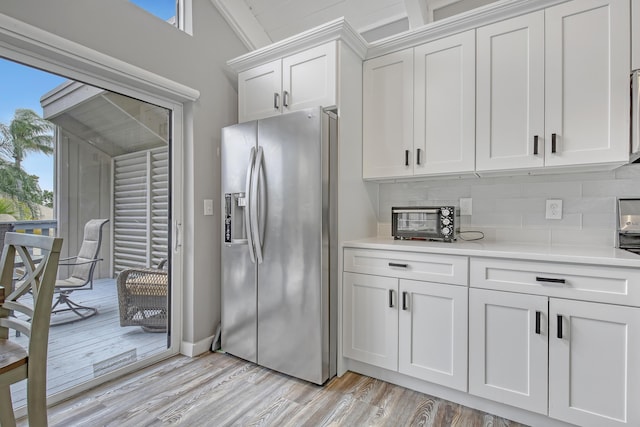 kitchen featuring decorative backsplash, white cabinetry, light wood-type flooring, and stainless steel fridge with ice dispenser