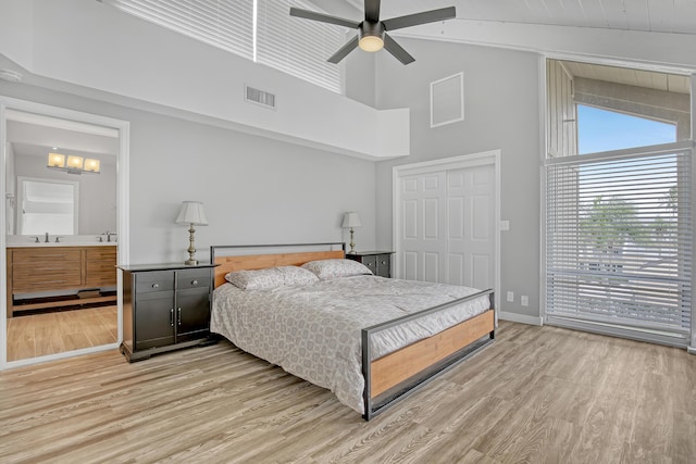 bedroom featuring ceiling fan, sink, high vaulted ceiling, light hardwood / wood-style floors, and a closet