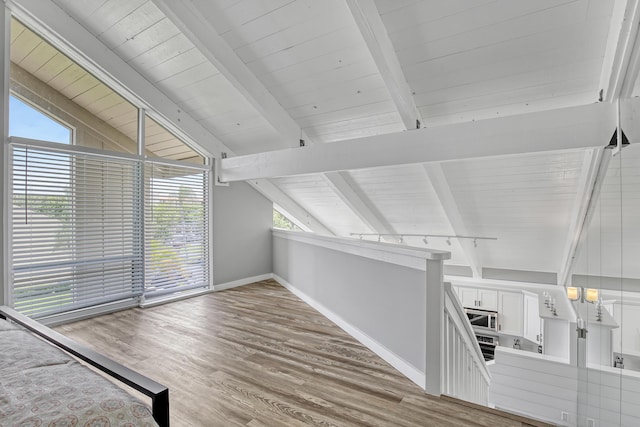 additional living space with lofted ceiling with beams and wood-type flooring