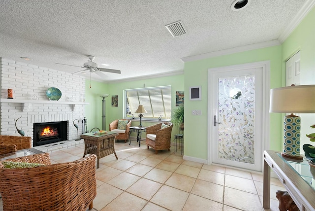 living room with ornamental molding, a textured ceiling, ceiling fan, a fireplace, and light tile patterned flooring