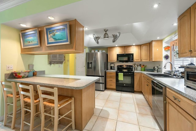 kitchen featuring black appliances, a kitchen breakfast bar, sink, light tile patterned flooring, and kitchen peninsula