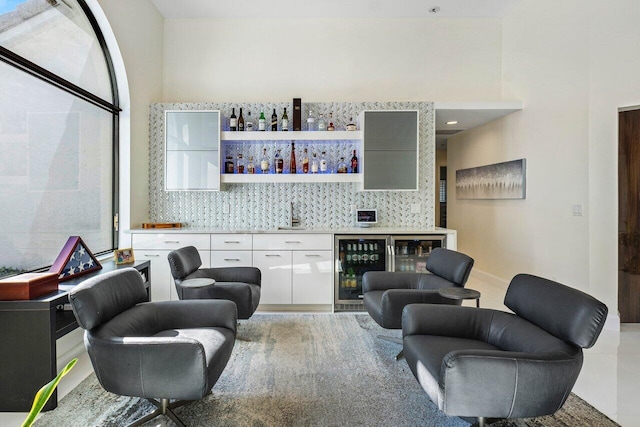 bar featuring white cabinetry, beverage cooler, and sink