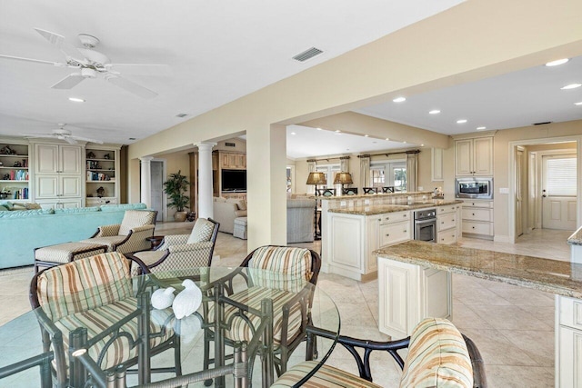 dining space featuring built in shelves, ceiling fan, and light tile patterned flooring