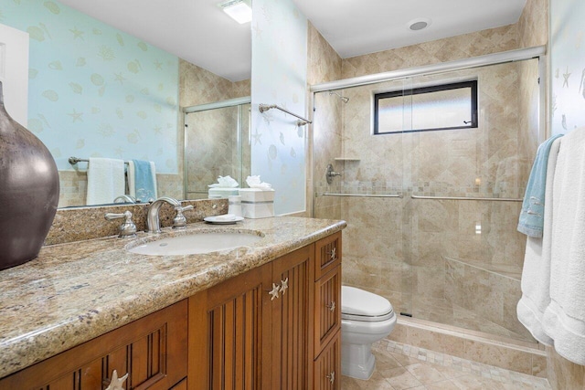 bathroom featuring a shower with door, vanity, and toilet