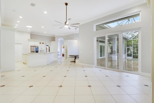 unfurnished living room with ceiling fan, ornamental molding, a high ceiling, and light tile patterned floors