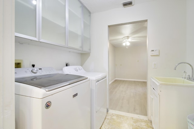 laundry area featuring cabinets, a textured ceiling, ceiling fan, sink, and washing machine and clothes dryer