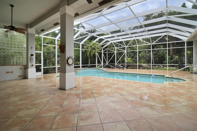 view of swimming pool featuring glass enclosure, ceiling fan, and a patio area