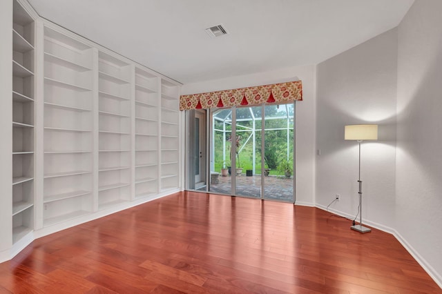 spare room with built in shelves and wood-type flooring