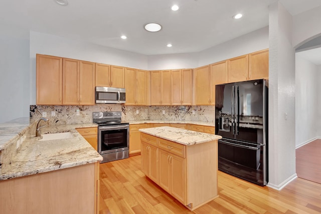 kitchen featuring light brown cabinets, sink, a kitchen island, light stone counters, and stainless steel appliances