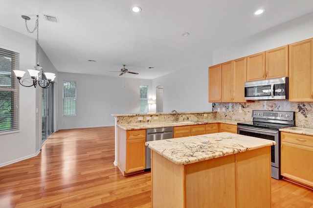 kitchen featuring pendant lighting, a center island, appliances with stainless steel finishes, tasteful backsplash, and kitchen peninsula