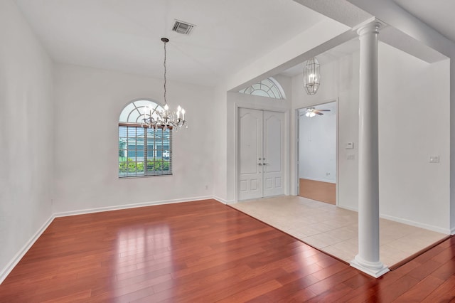 entrance foyer featuring decorative columns, light hardwood / wood-style flooring, and ceiling fan with notable chandelier