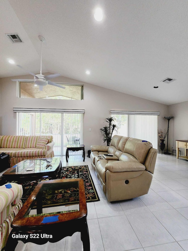 tiled living room featuring lofted ceiling, a wealth of natural light, and a textured ceiling