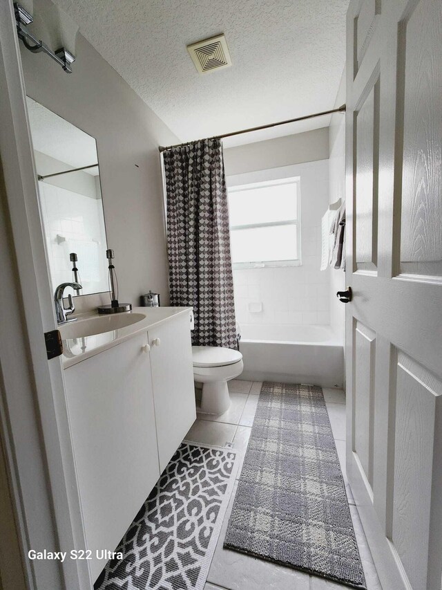 full bathroom featuring toilet, a textured ceiling, vanity, shower / bath combination with curtain, and tile patterned flooring